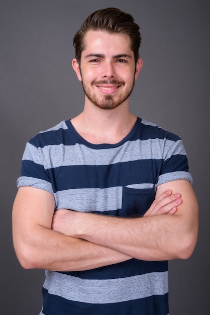 Joven guapo con barba contra la pared gris