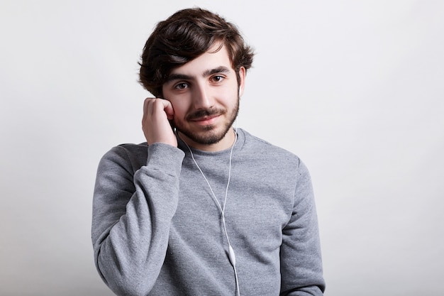 Joven guapo con barba hipster con peinado de moda de pie sobre blanco