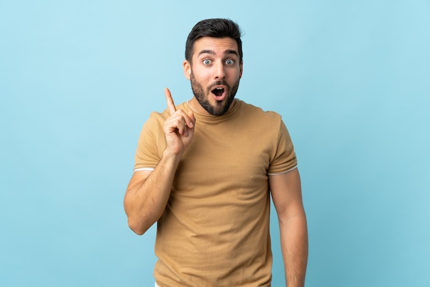 Joven guapo con barba con la intención de darse cuenta de la solución mientras levanta un dedo