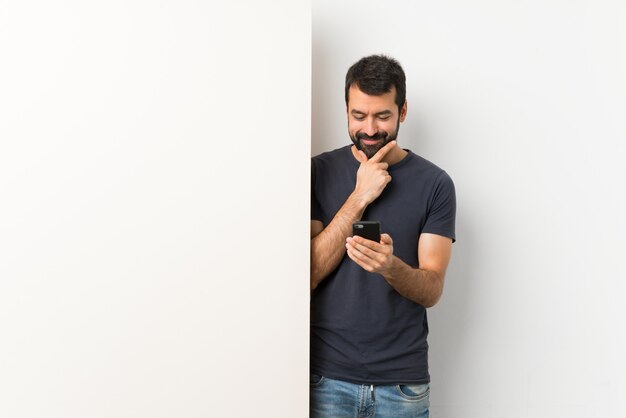 Joven guapo con barba pensando y enviando un mensaje