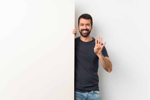 Joven guapo con barba sosteniendo una gran pancarta vacía