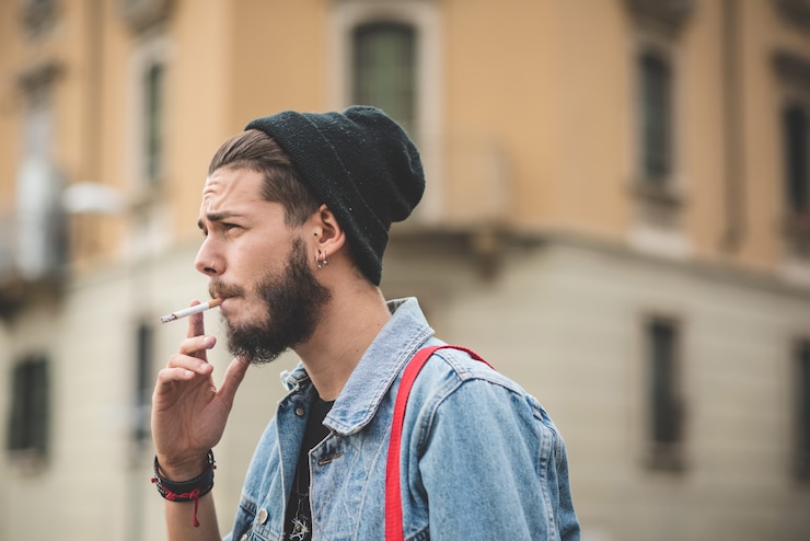 Foto joven guapo barbudo hipster hombre fumar cigarrillo