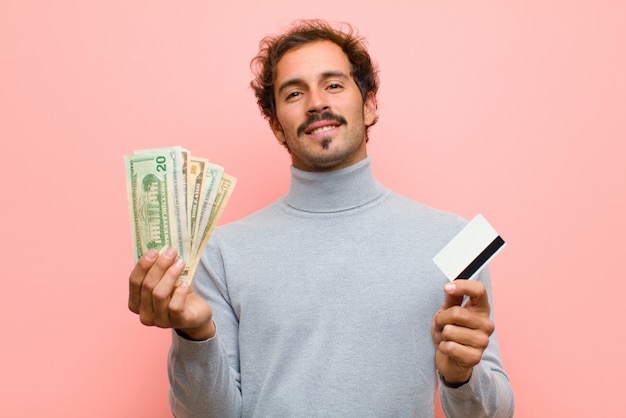 Joven guapo con billetes de dólar rosa pared plana