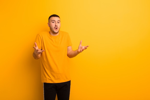 Joven guapo con la boca abierta y asombrado, sorprendido y asombrado con una increíble sorpresa contra la pared