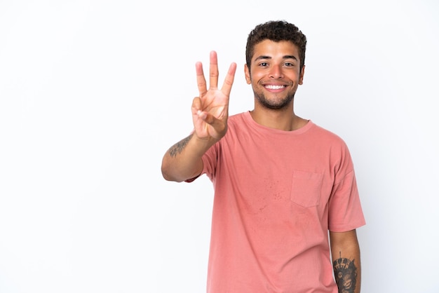 Foto joven guapo brasileño aislado sobre fondo blanco feliz y contando tres con los dedos