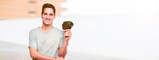 Joven guapo bronceado con una cámara de cine vintage