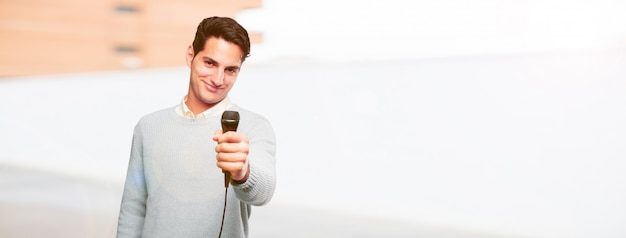 Foto joven guapo bronceado con un micrófono