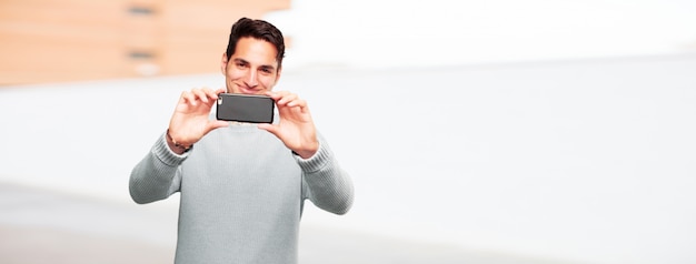 Joven guapo bronceado con un teléfono inteligente con pantalla táctil