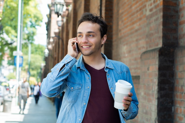 Joven guapo con café desechable