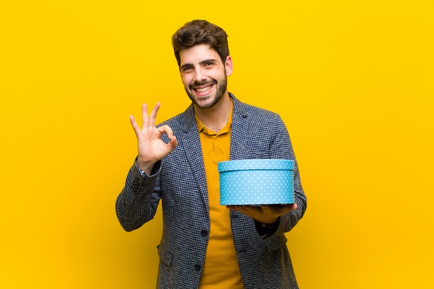 Joven guapo con una caja contra naranja