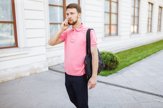 Joven guapo caminando por la ciudad y hablando por teléfono, hipster