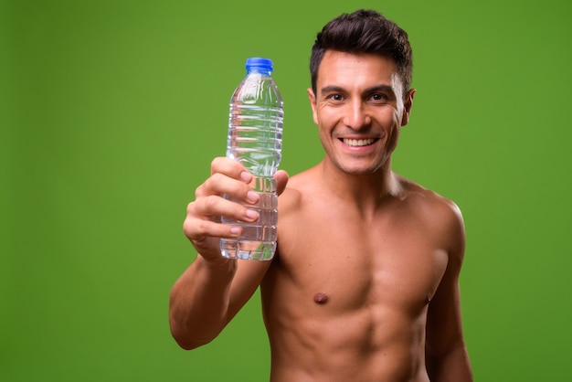 Joven guapo sin camisa contra verde