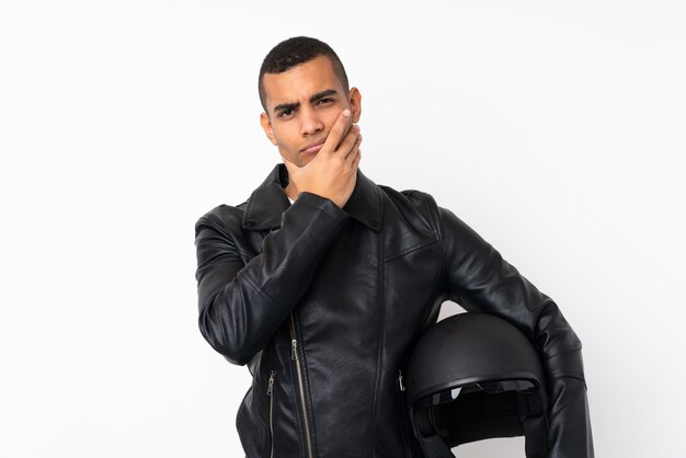 Joven guapo con un casco de moto sobre pared blanca aislada pensando en una idea