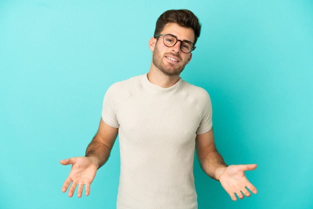 Joven guapo caucásico aislado sobre fondo azul feliz y sonriente