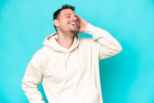 Joven guapo caucásico aislado sobre fondo azul sonriendo mucho