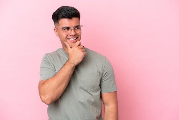 Joven guapo caucásico aislado sobre fondo rosa mirando hacia el lado y sonriendo