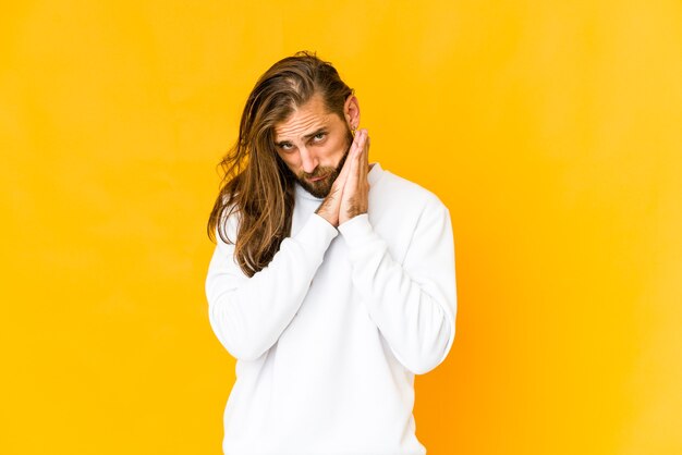 Joven guapo caucásico de pelo largo expresando emociones aisladas