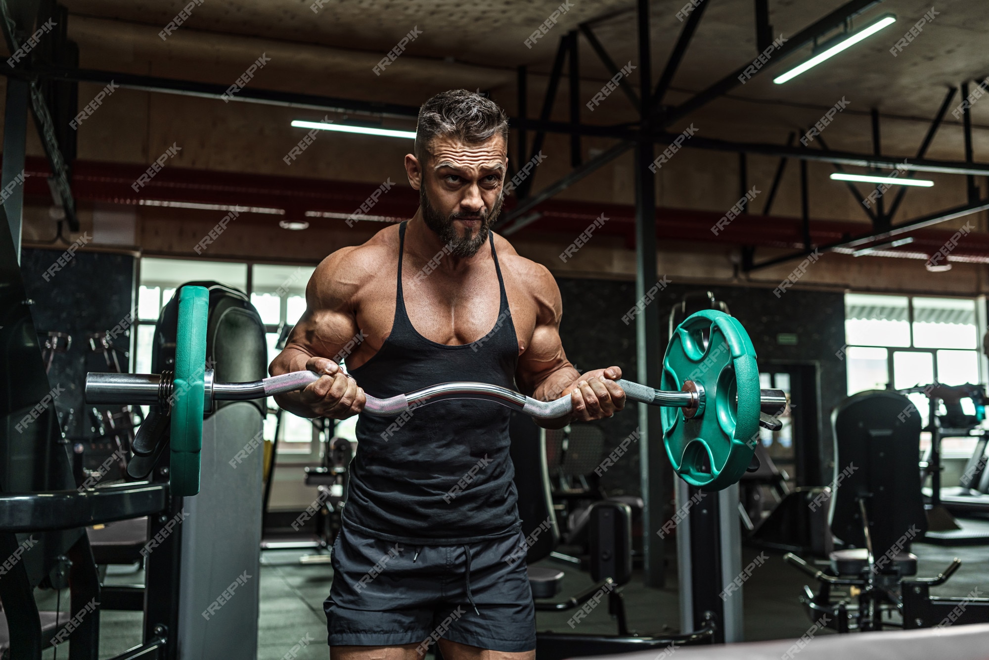 Joven y guapo deportista culturista levantador de pesas con un cuerpo  ideal, después de entrenar posa frente a la cámara, músculos abdominales,  bíceps, tríceps. en ropa deportiva.