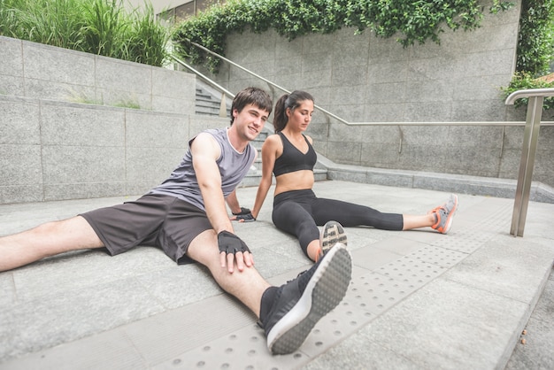 joven guapo deportivo hombre y mujer que se extiende