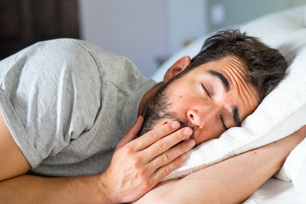 Joven guapo durmiendo en la cama