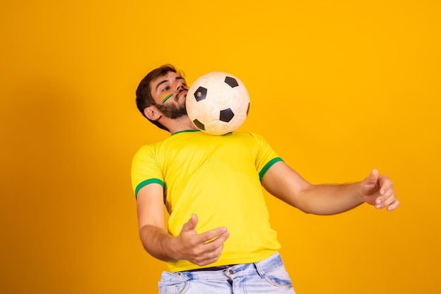 Joven guapo fanático de Brasil jugando con una pelota de fútbol