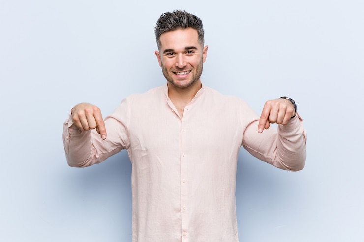 Foto joven guapo fresco apunta hacia abajo con los dedos, sentimiento positivo.