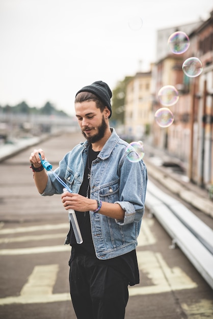 joven guapo hipster barbudo soplando burbujas jabón