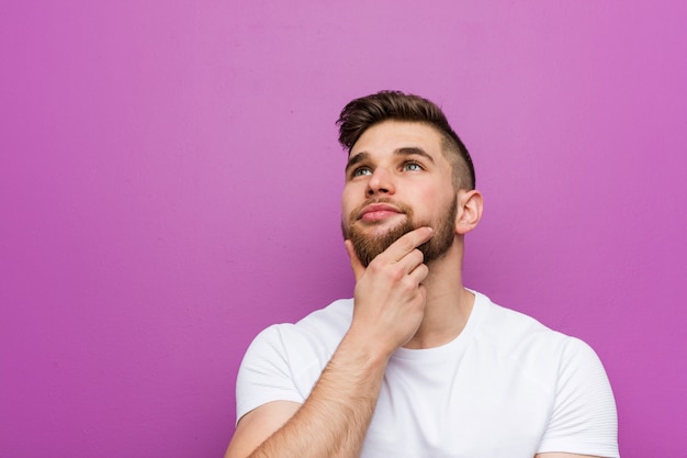 Joven guapo hombre caucásico de lado con expresión dudosa y escéptica.