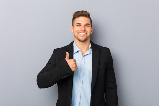 Joven guapo hombre caucásico sonriendo y levantando el pulgar hacia arriba