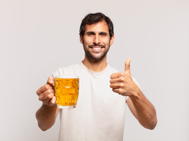 Joven guapo indio expresión feliz y sosteniendo una cerveza