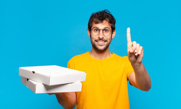 Joven guapo indio expresión feliz y sosteniendo pizzas para llevar