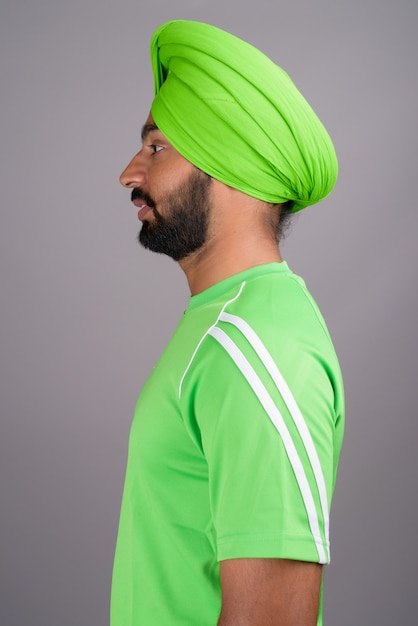 Joven guapo indio sij hombre vestido con turbante y camisa verde