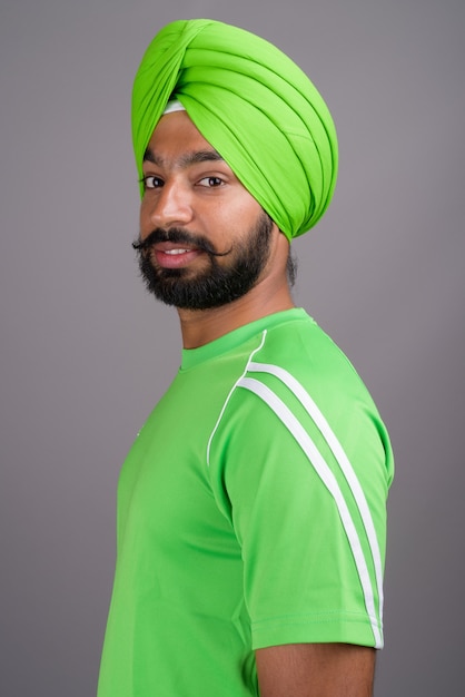 Joven guapo indio sij hombre vestido con turbante y camisa verde