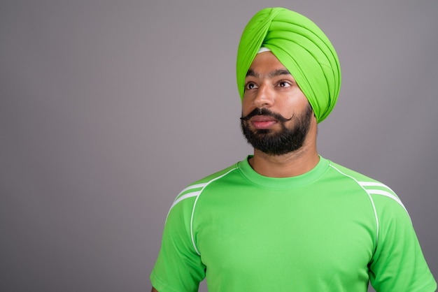 Joven guapo indio sij hombre vestido con turbante y camisa verde