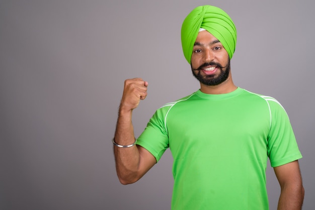 Joven guapo indio sij hombre vestido con turbante y camisa verde