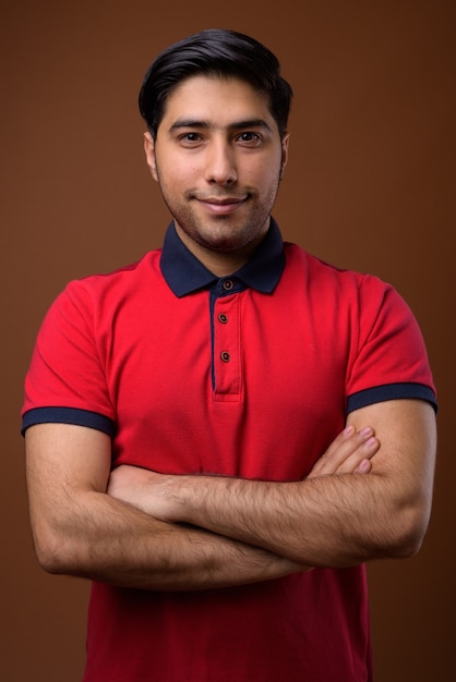 Foto joven guapo iraní contra la pared marrón