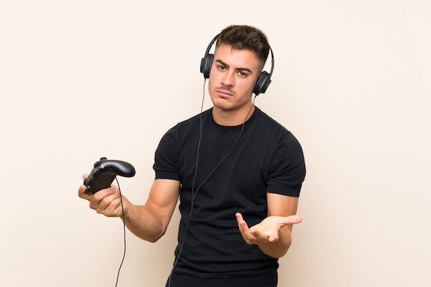 Joven guapo jugando con un controlador de videojuego sobre pared