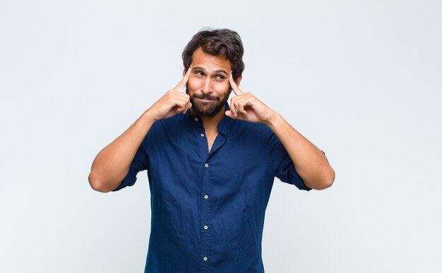 Joven guapo latino mirando concentrado y pensando mucho en una idea, imaginando una solución a un desafío o problema