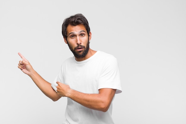 Joven guapo latino que se siente extremadamente conmocionado y sorprendido, ansioso y en pánico, con una mirada estresada y horrorizada