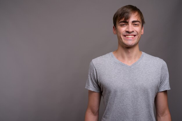 Joven guapo listo para gimnasio contra el fondo gris