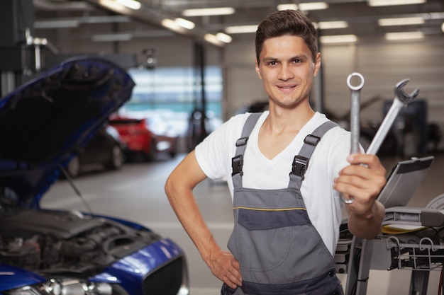 Joven guapo mecánico reparando el vehículo en su garaje