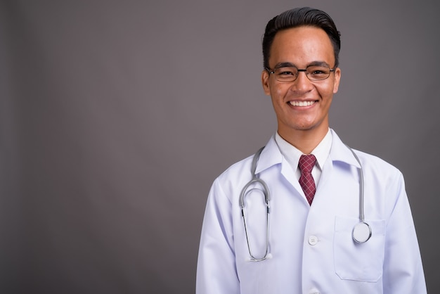 Joven guapo médico indio contra la pared gris