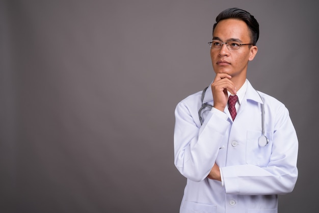 Joven guapo médico indio contra la pared gris