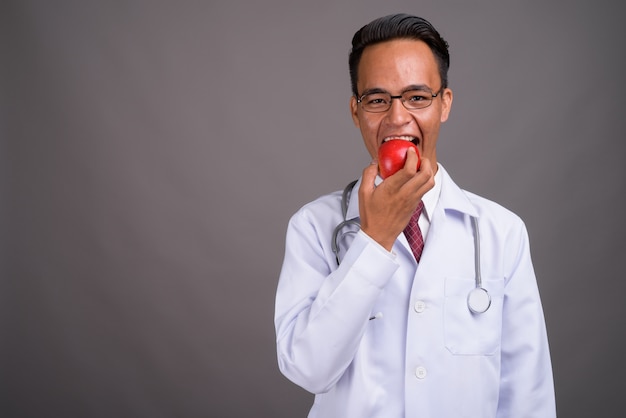 Joven guapo médico indio contra la pared gris