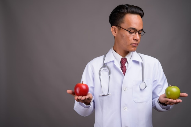 Joven guapo médico indio contra la pared gris