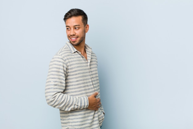 Joven guapo mira a un lado sonriente, alegre y agradable