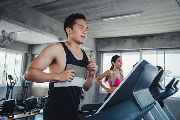 Joven guapo en modernas cintas de correr eléctricas en el gimnasio. Corriendo en cinta.