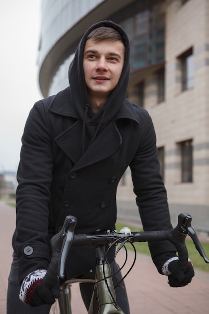 Joven guapo montando bicicleta en la ciudad