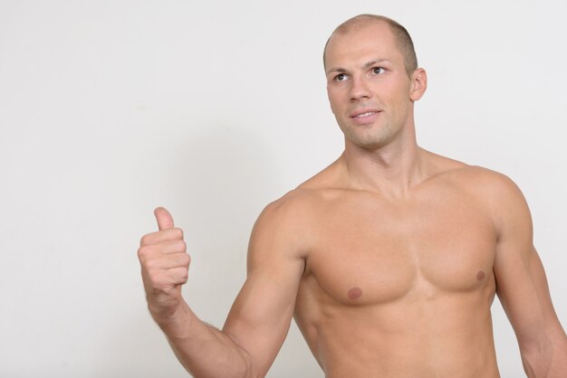 Joven guapo musculoso calvo sin camisa contra el espacio en blanco