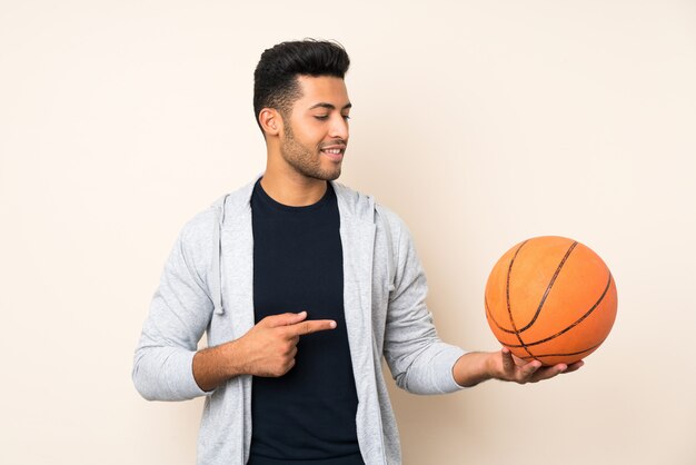 Joven guapo con pelota de baloncesto y apuntando